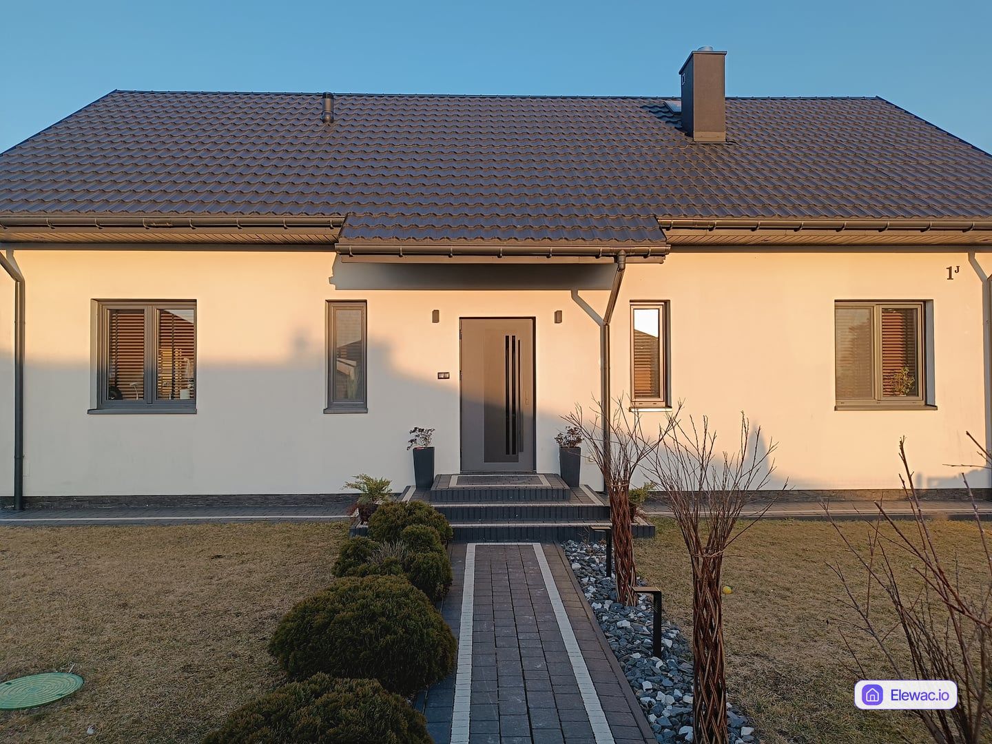 Dom jednorodzinny z lat 2000. z białym tynkiem i antracytowym dachem przed remontem elewacji